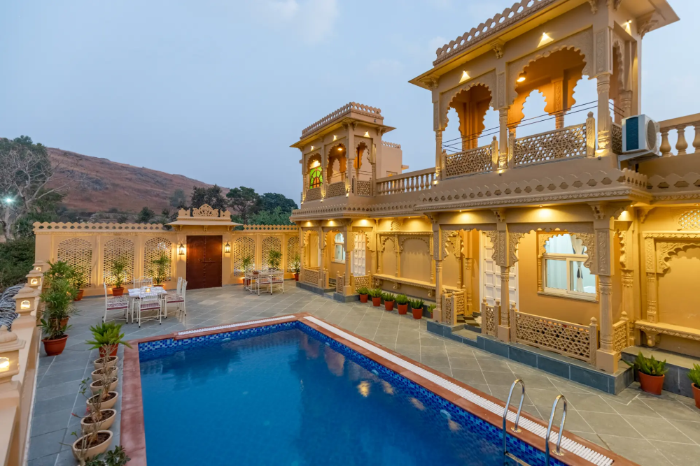 Royal palace-style villa in Udaipur with pool, poolside dining, and colored glass reflecting traditional royal look